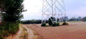 Acerra, terreno a dx e strada interpoderale a sx con cumulo di rifiuti visibili in fondo,